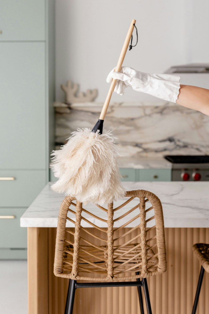 A gloved hand dusting a marble kitchen island